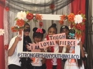 Girls holding up a sign, which reads: I am loyal, tough, fierce. #strongerthanyouthinklaco