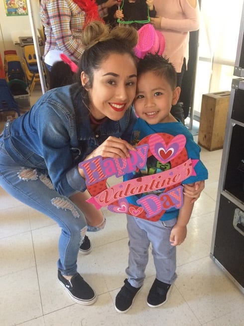 Young woman and boy holding a Happy Valentines Day sign.