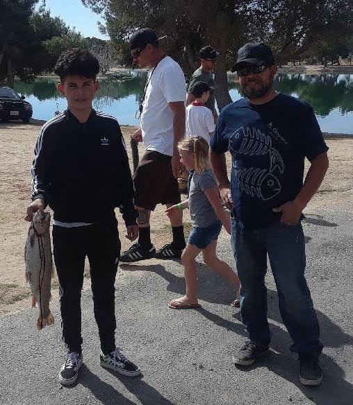 Families at a lake. Some holding fish