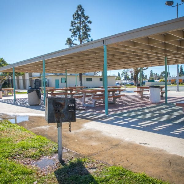BBQ grills next to picnic tables under an awning