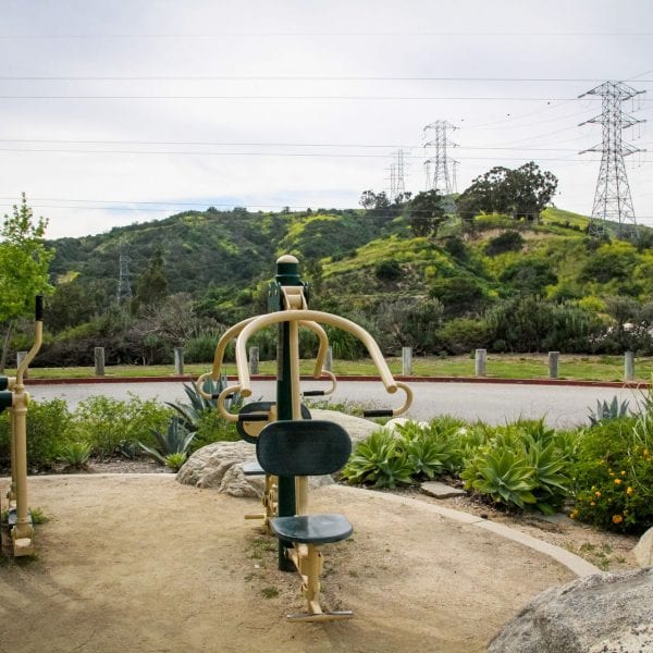 Exercise equipment over looking a walking path and green hills