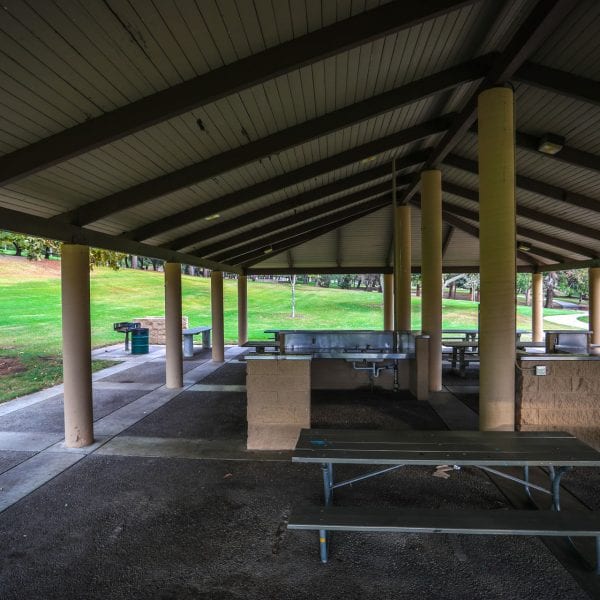 Picnic tables and kitchen area under an awning. BBQ grills just outside