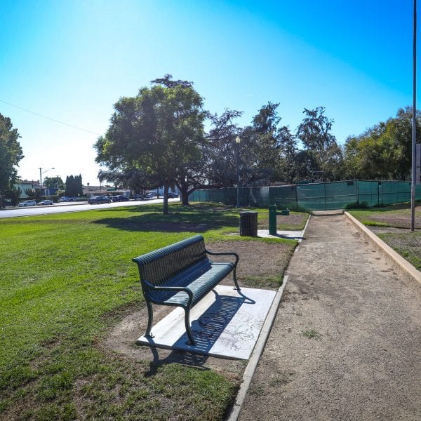 Bench, trash can and drinking fountain next to walkway