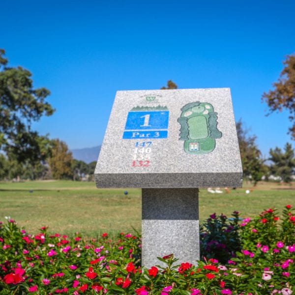Hole 1 sign amongst flowers and golf course
