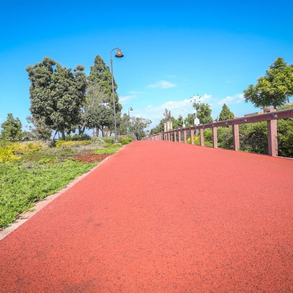 Red exercise track running along a garden and fence