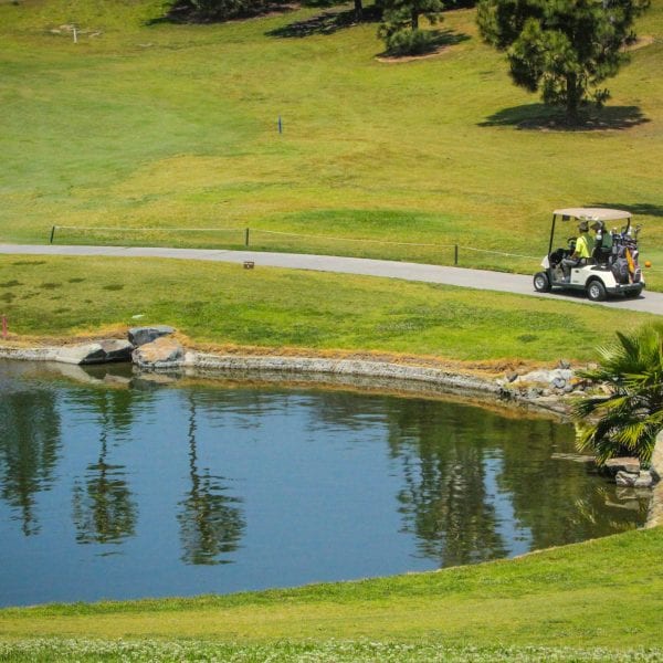 People driving a golf cart around a lake