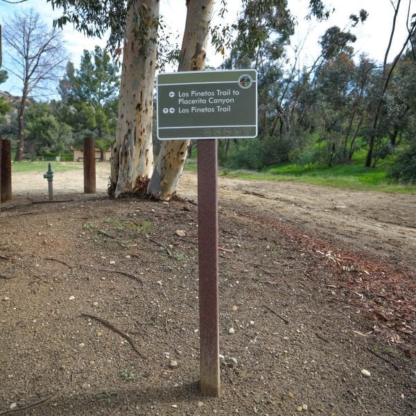 Directional sign among trees and a dirt paths