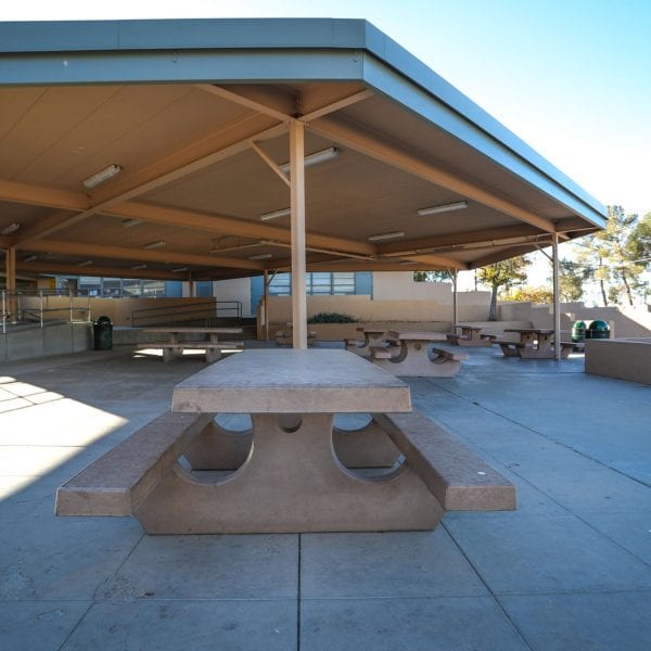 Picnic tables under an awning near a facility