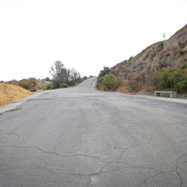 Paved road on hill. Bench and sign to the right